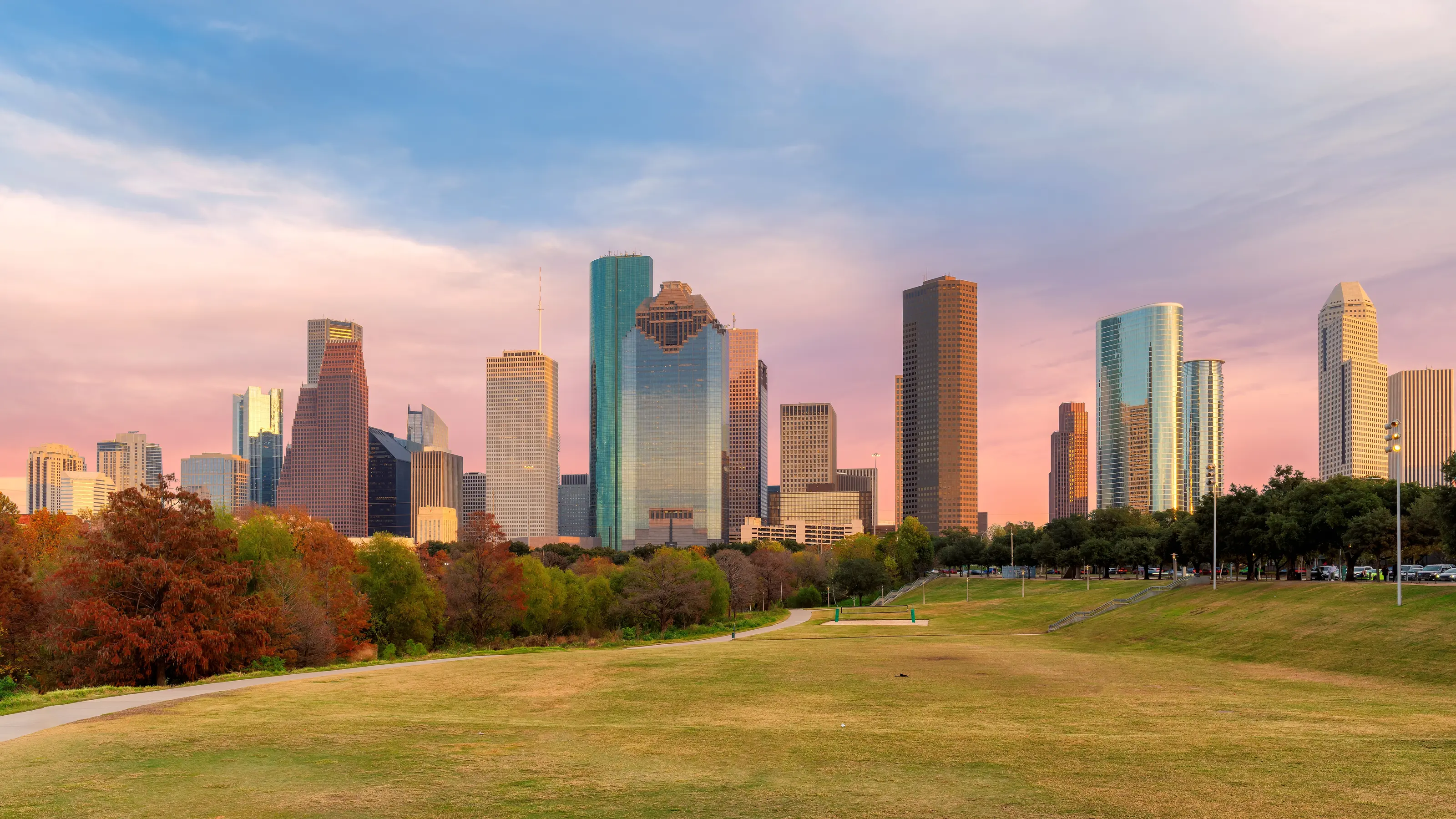 The Houston skyline at dusk seen across a park lawn