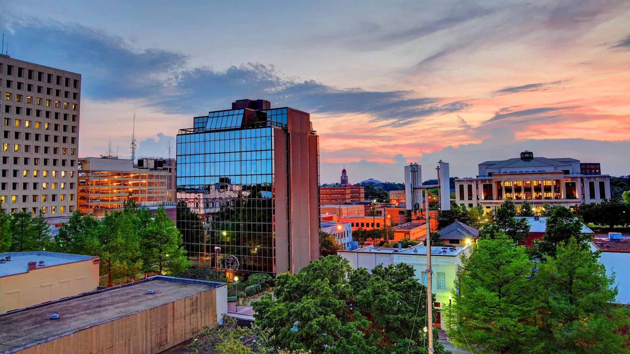 Downtown Lafayette, Louisiana at sunset, with its glass office tower among the trees