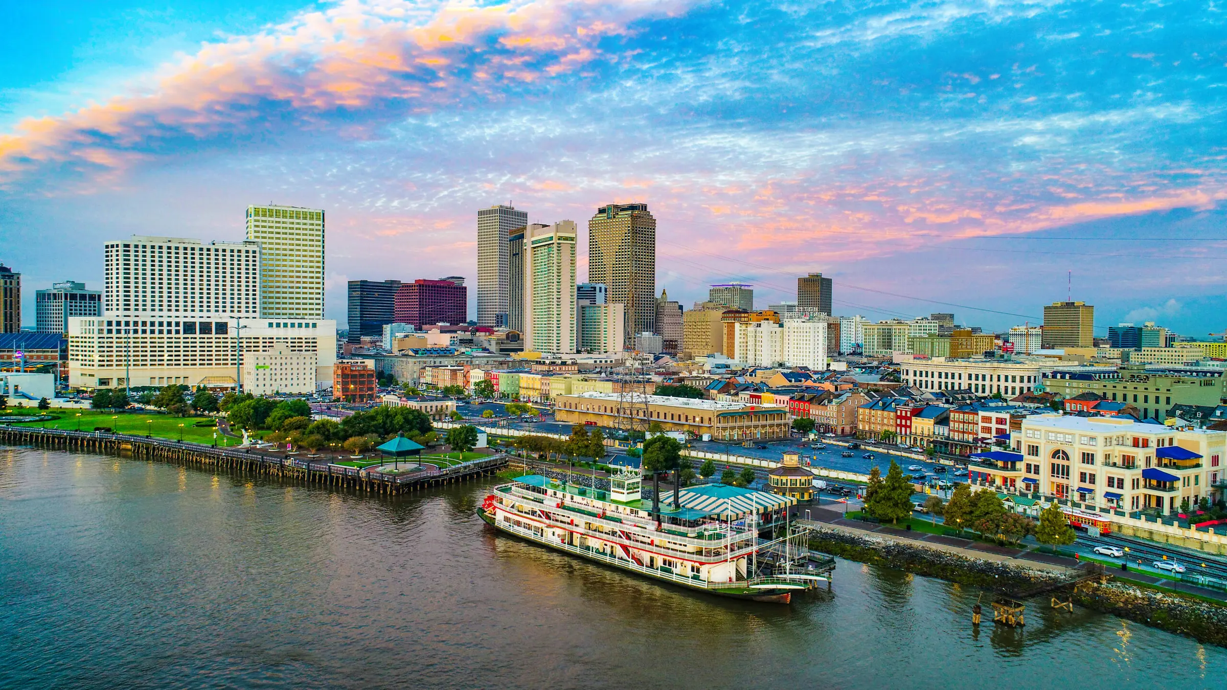 The New Orleans skyline at sunset from across the Mississippi River, with a paddle steamer at the wharf